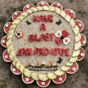 Circular decorative platter, bordered by pineapple and watermelon, on a granular base